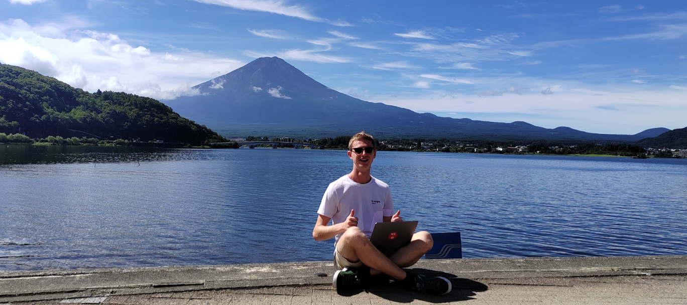 Cedric working remotely beside Lake Kawaguchi with Mount Fuji behind him